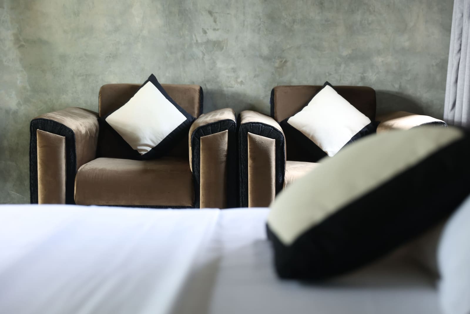 Inside the lakeside cottage at Aji Fruit Farm — velvet armchairs against raw concrete walls